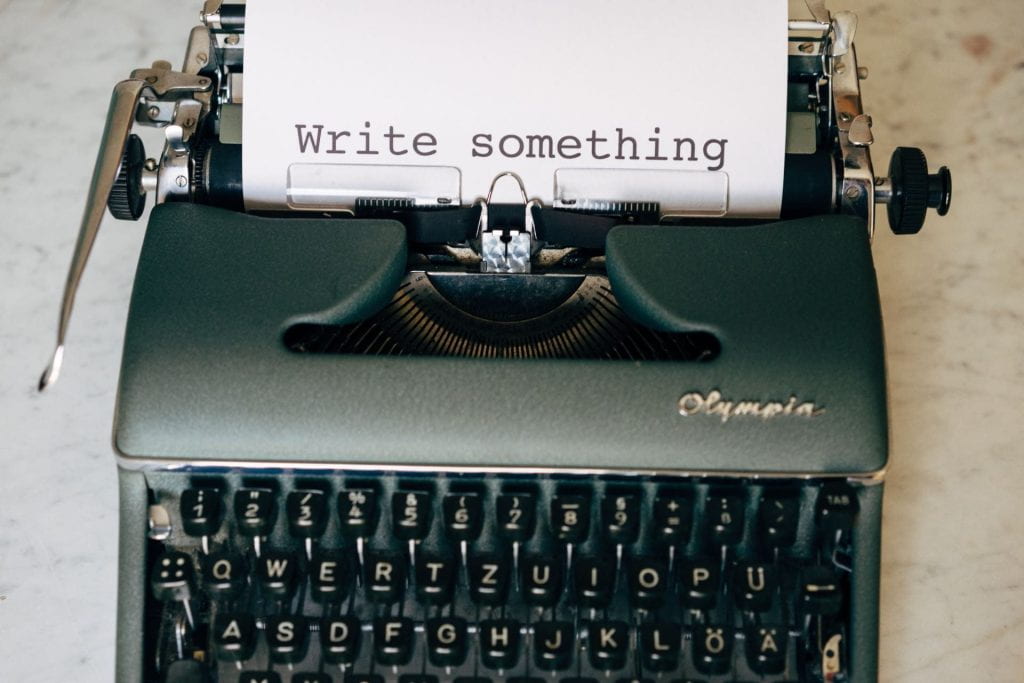 A classic typewriter displays the text 'write something.'